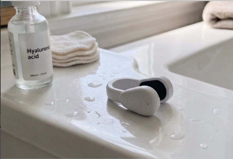 Ozlura device resting on a bathroom counter next to serum